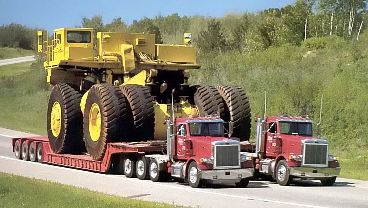 two articulated semi trucks hauling mining truck